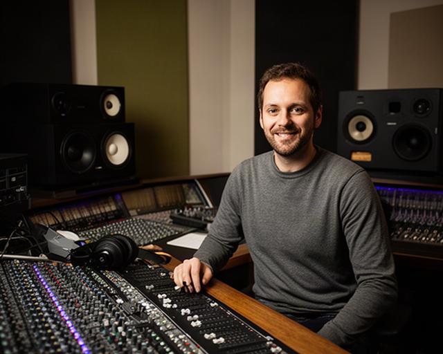 Audio engineer Kazim Freudenau in de regieruimte naast een mengtafel en studiomonitors